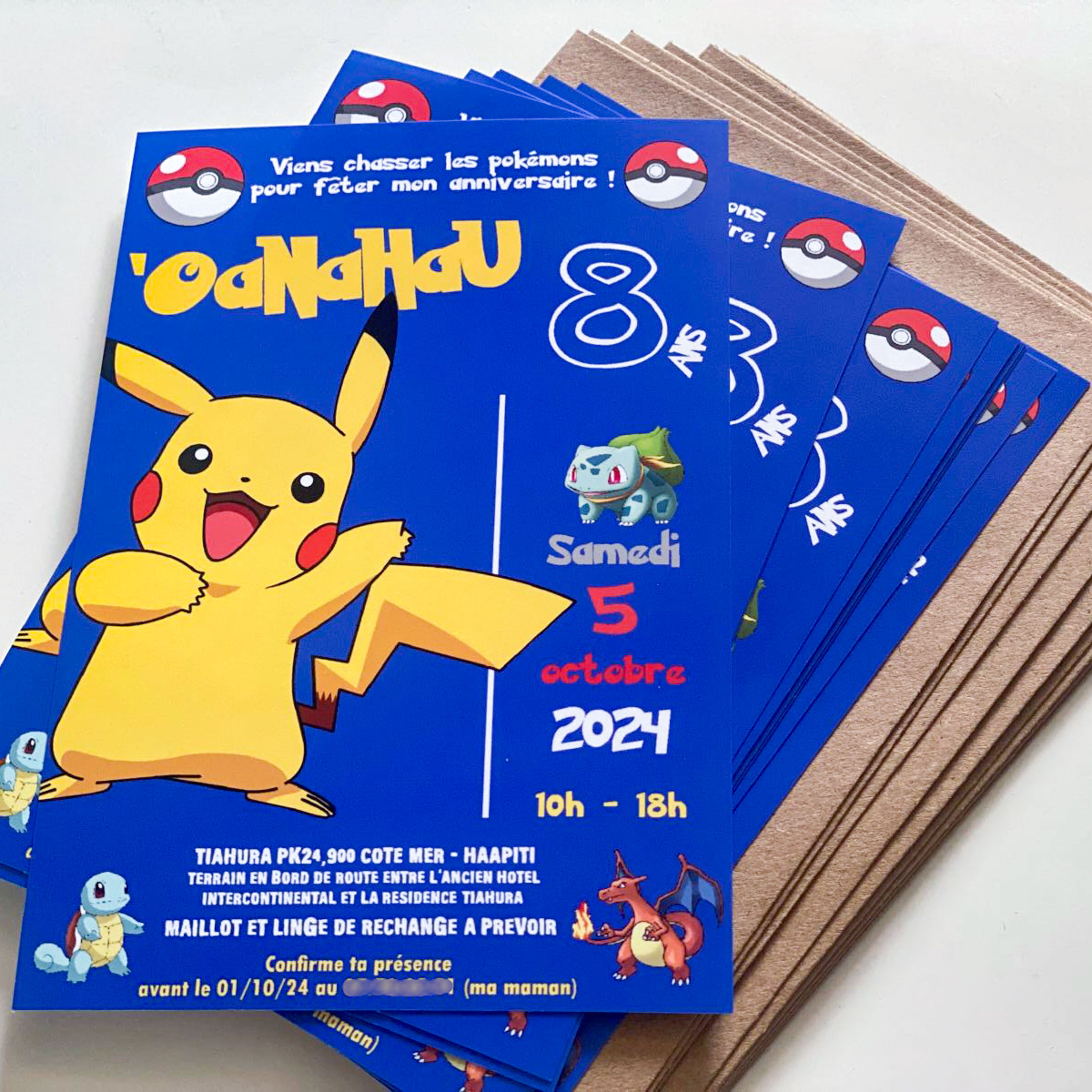 Photo de cartes d’invitation imprimées 10x15cm thème Pokémon : fond bleu roi, grand Pikachu à gauche, Bulbizarre et Dracaufeu, Poké Balls en frise, mentions “8 ans – samedi 5 octobre 2024 – 10h-18h”, cartes empilées avec enveloppes kraft.