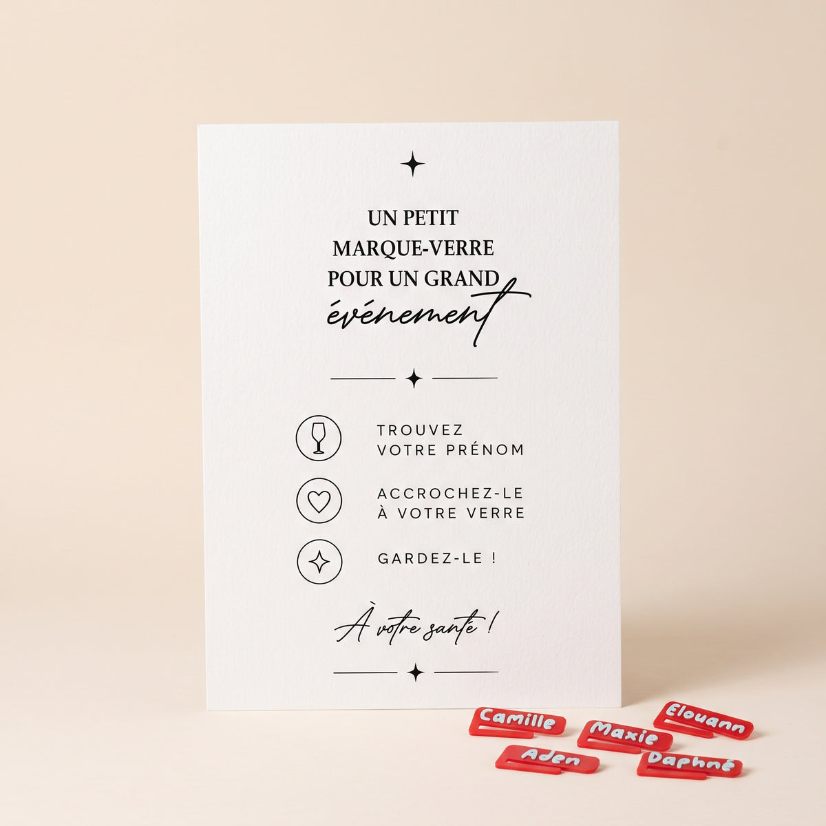 Packshot carré de l’affiche événementielle « Un petit marque-verre pour un grand événement » sur papier blanc texturé, présentée au centre sur un fond uni beige clair pastel et lumineux. En bas à droite, plusieurs petits marque-verres Bigoût et personnalisés (Camille, Maxie, Aden, Elouann et Daphné) accompagnent l’affiche pour illustrer les étapes destinées aux invités.