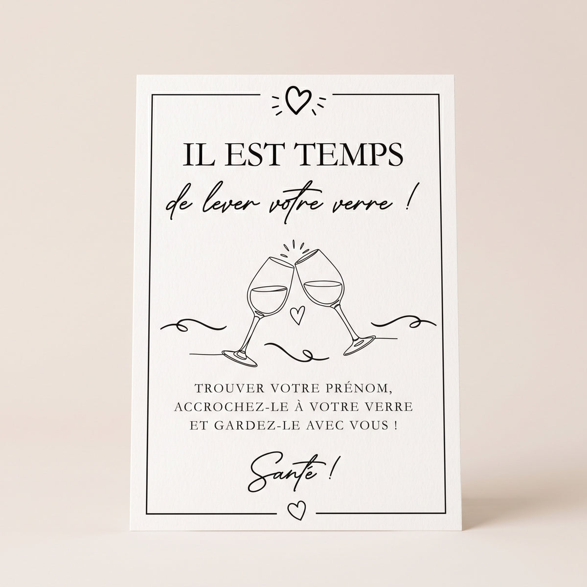 Un packshot carré et épuré de l'affiche, imprimée sur un papier mat blanc naturel et de haute qualité, posée debout au centre de l’image. Le visuel de l’affiche, avec ses illustrations de deux verres à vin qui trinquant et ses petits cœurs, est accompagné des textes noirs « IL EST TEMPS de lever votre verre ! », « TROUVER VOTRE PRÉNOM, ACCROCHEZ-LE À VOTRE VERRE ET GARDEZ-LE AVEC VOUS ! » et « Santé ! ». 
