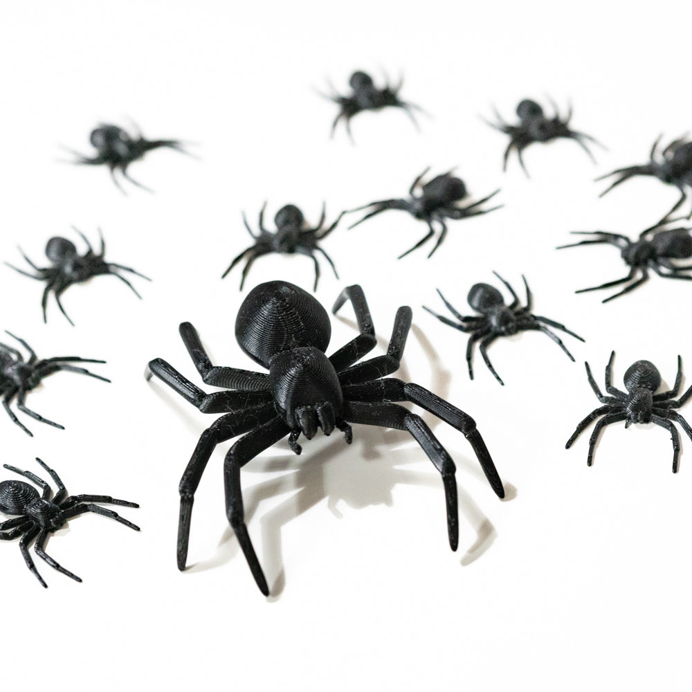 Lot d’araignées noires décoratives imprimées en 3D (PLA) : une grande araignée au centre et plusieurs petites autour, finition plastique mate, photographiées sur fond blanc — décoration Halloween pour table, buffet, vitrine ou chasse au trésor.