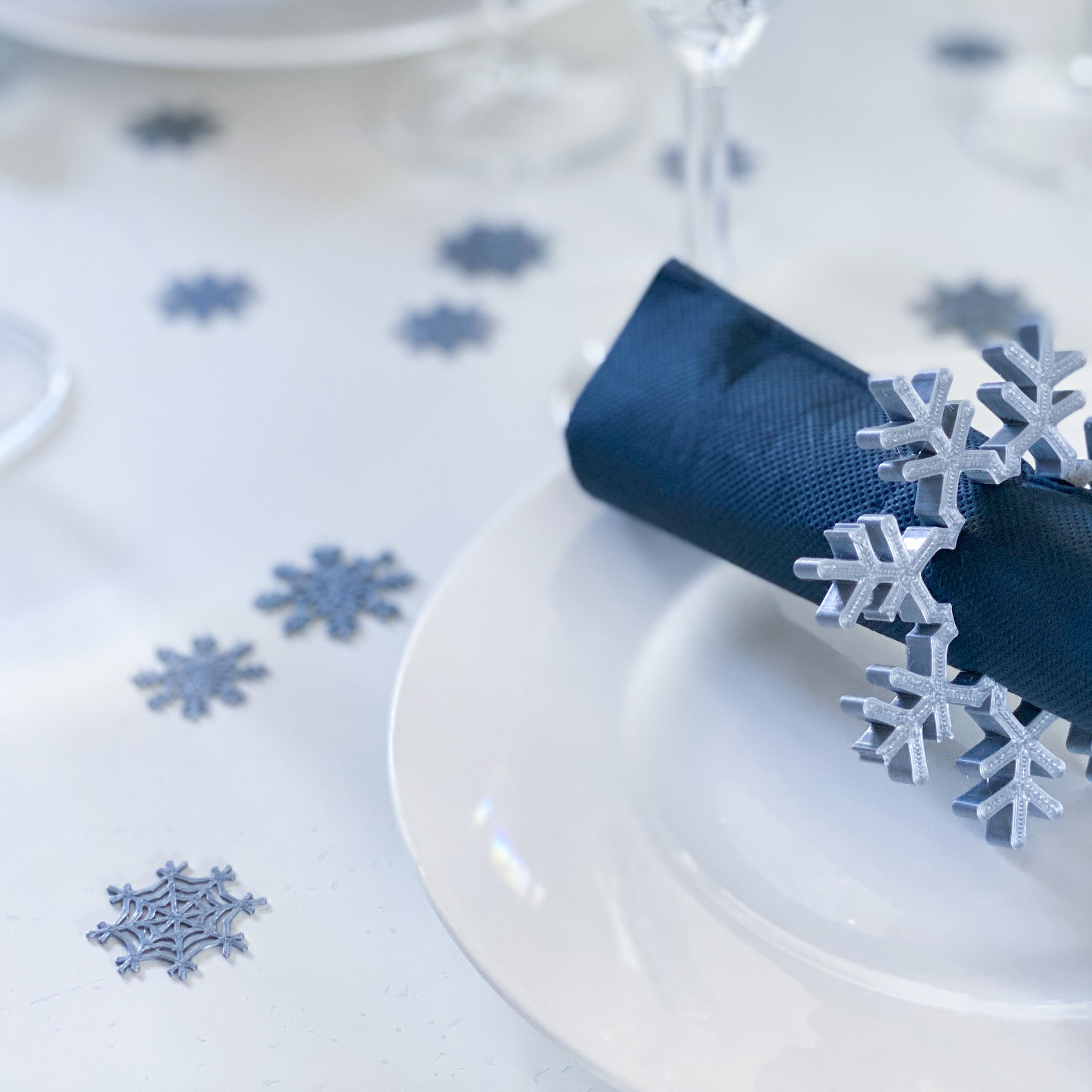 Confettis flocons de neige et rond de serviette flocon sur une table d’hiver élégante.