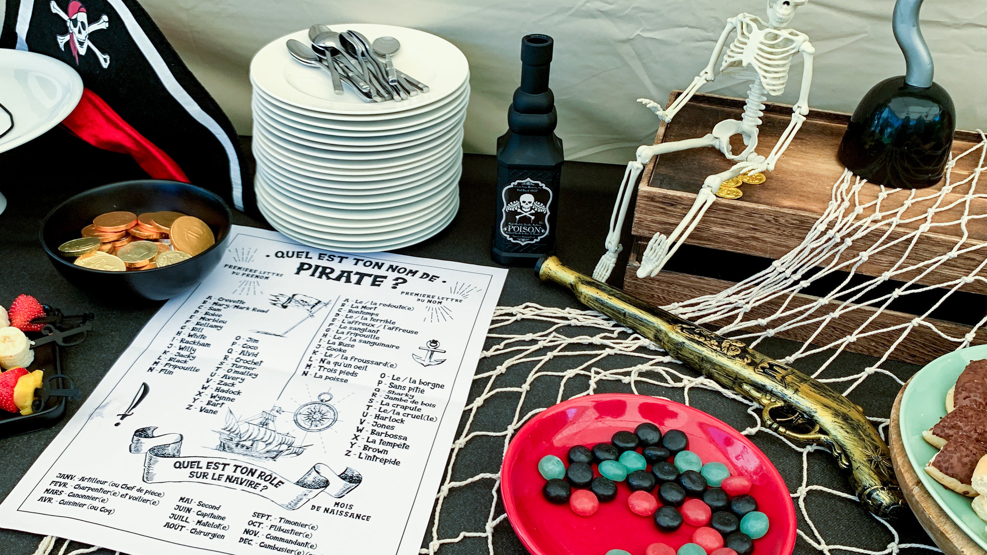 Table décorée sur le thème des pirates avec pièce d’or, squelette, accessoires, bonbons et l’affiche “Quel est ton nom de pirate ?”, prête à accueillir les invités et à lancer le jeu d’immersion.