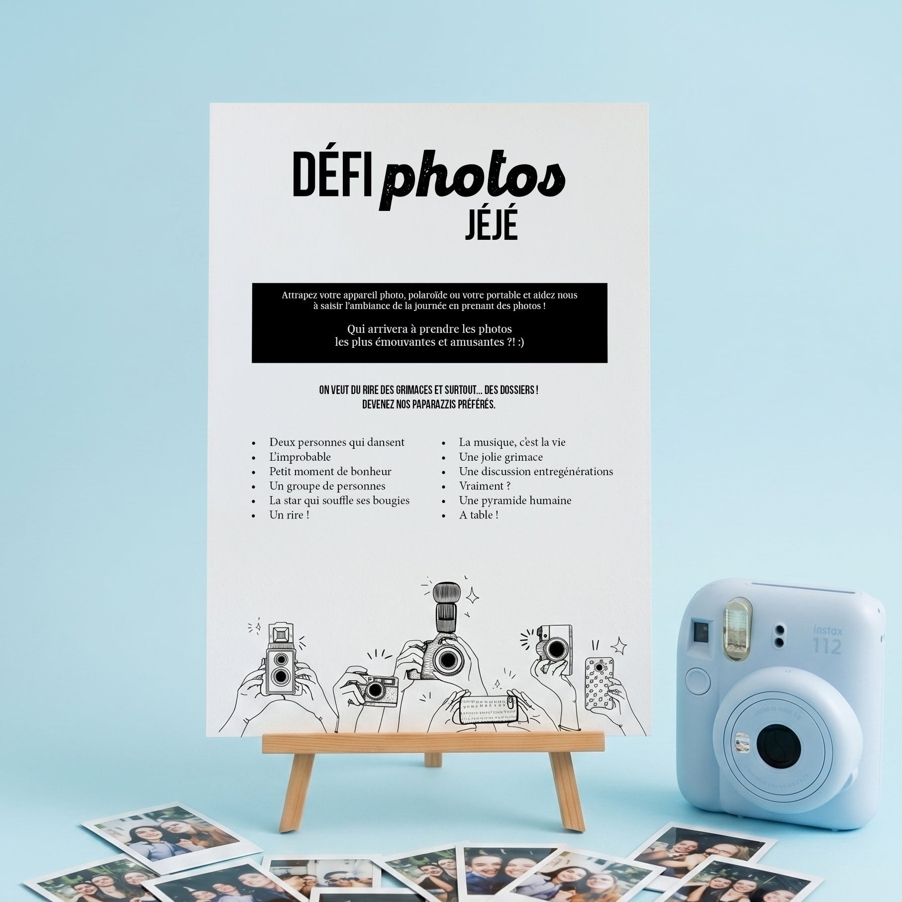 Packshot format carré d'une affiche de jeu d'anniversaire 'DÉFI photos JÉJÉ' posée sur un petit chevalet en bois. L'affiche blanche présente une liste de défis originaux et une illustration de mains tenant des appareils photo. Elle est mise en scène sur un fond uni bleu pastel lumineux, accompagnée d'un appareil photo instantané bleu ciel et de plusieurs mini photos polaroïd éparpillées au premier plan.