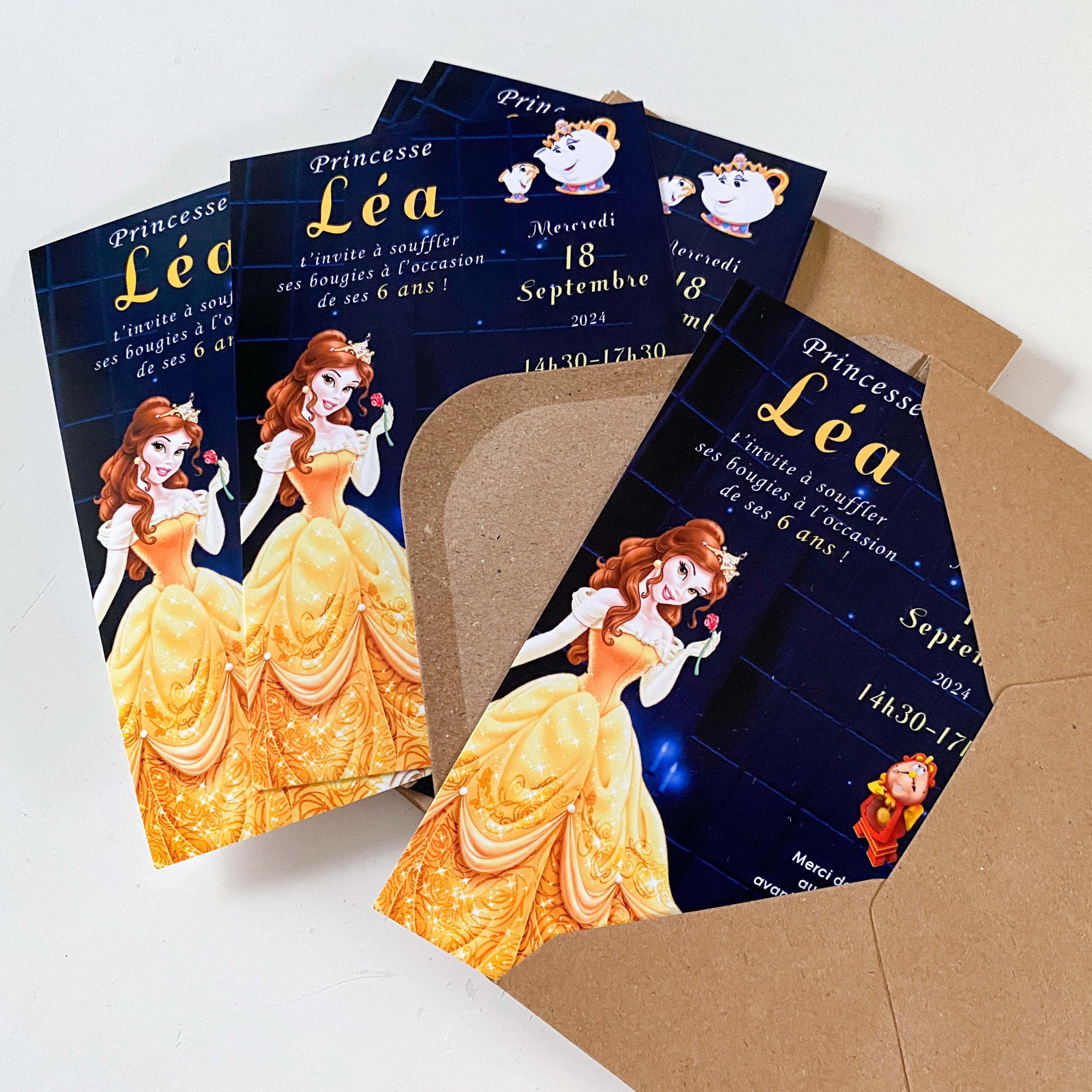 Plusieurs invitations d’anniversaire posées avec des enveloppes kraft ouvertes. Visuel principal : princesse en grande robe jaune dorée tenant une rose, sur fond bleu nuit étoilé. Texte lisible : “Princesse Léa”, date et horaire en typographie dorée.