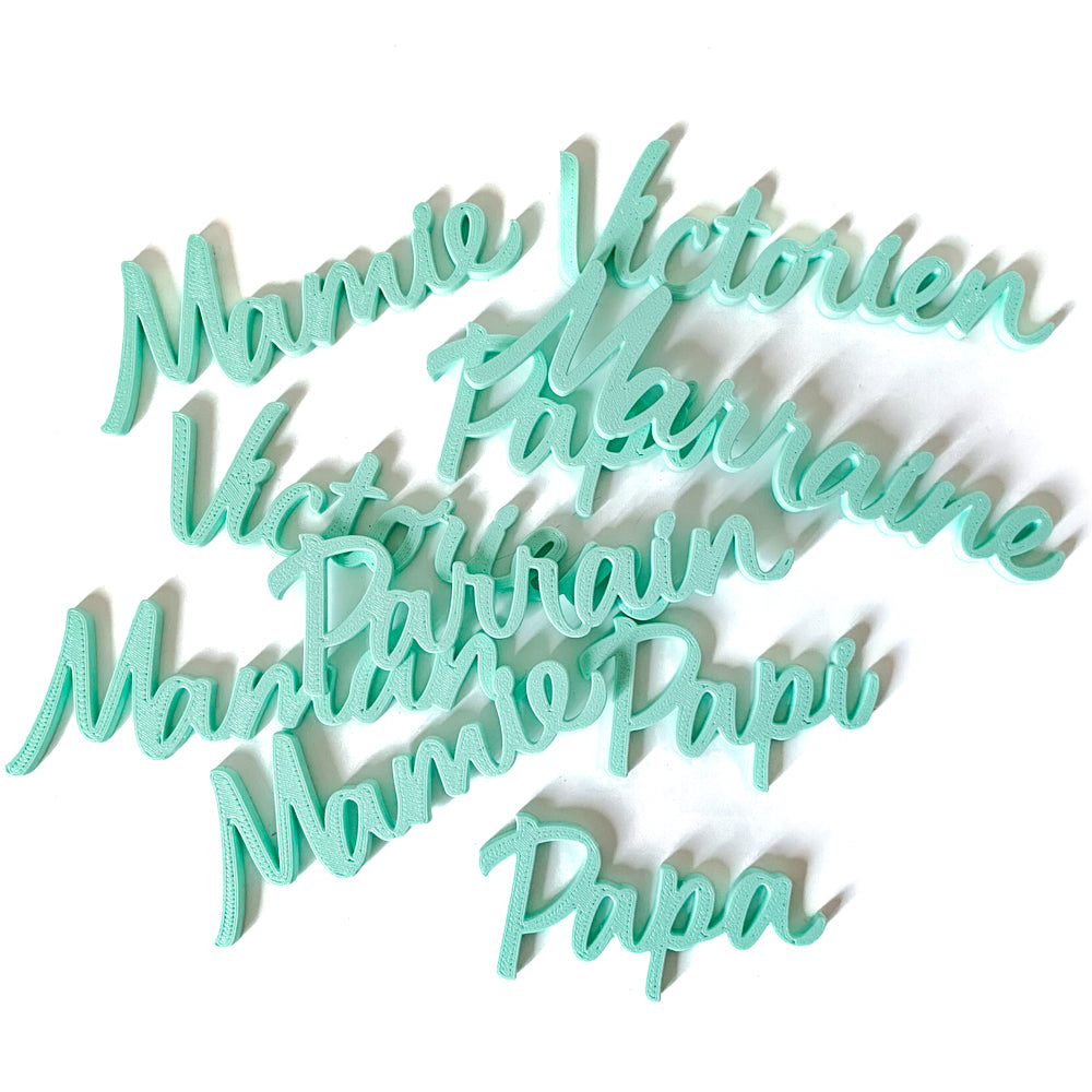 Ensemble de marque-places familiaux en PLA vert d’eau, comprenant Mamie, Papi, Parrain, Marraine, Papa et prénoms personnalisés, réalisés en impression 3D pour décorer une table de fête.