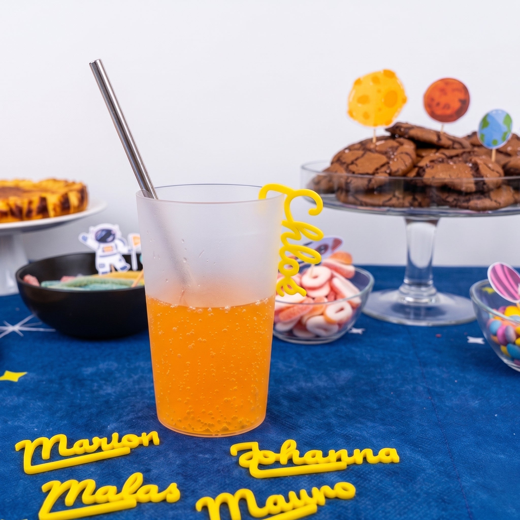 Marque-verre personnalisé jaune imprimé en 3D avec le prénom Chloé, clipsé sur un verre de jus d'orange lors d'un anniversaire enfant sur le thème de l'espace.