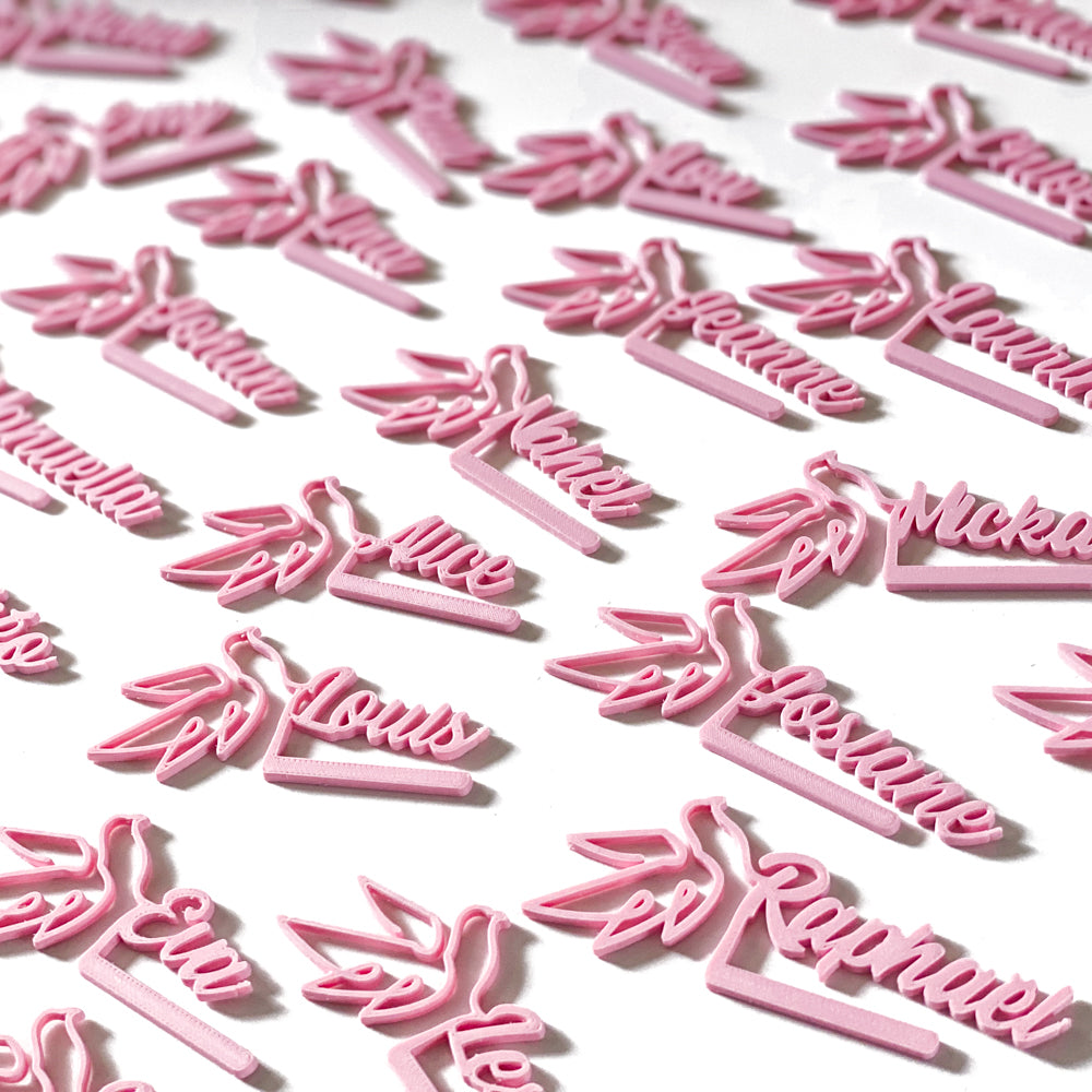 Marque-verres Colombe roses personnalisés disposés en série, avec prénoms en écriture cursive et silhouette de colombe.