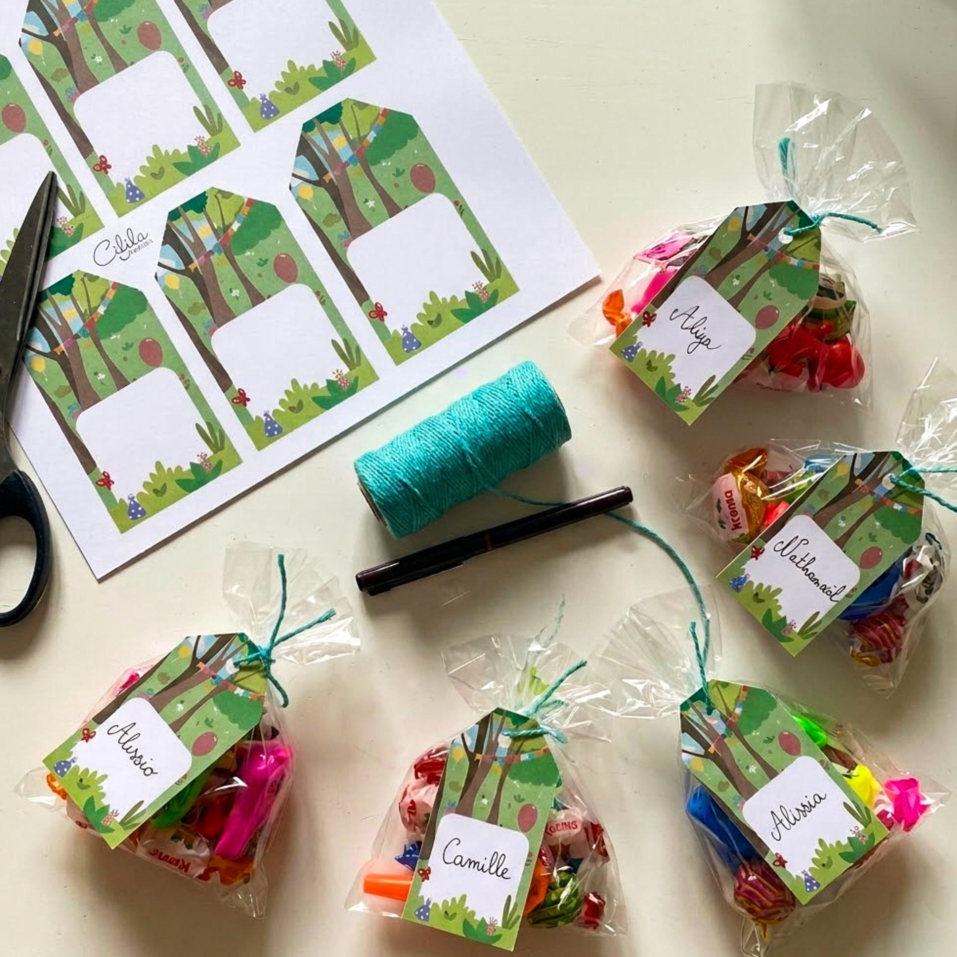 Planche d'étiquettes cadeaux anniversaire thème forêt à imprimer, avec des sachets de bonbons décorés de prénoms écrits à la main.