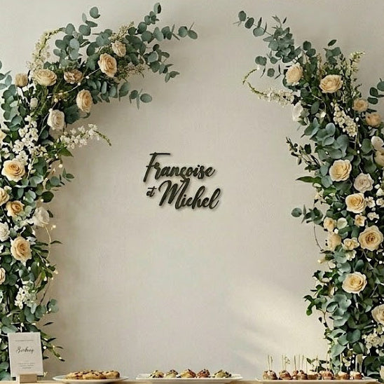 Prénoms « Françoise et Michel » en décoration murale en impression 3D, sur un mur avec arche florale de mariage.