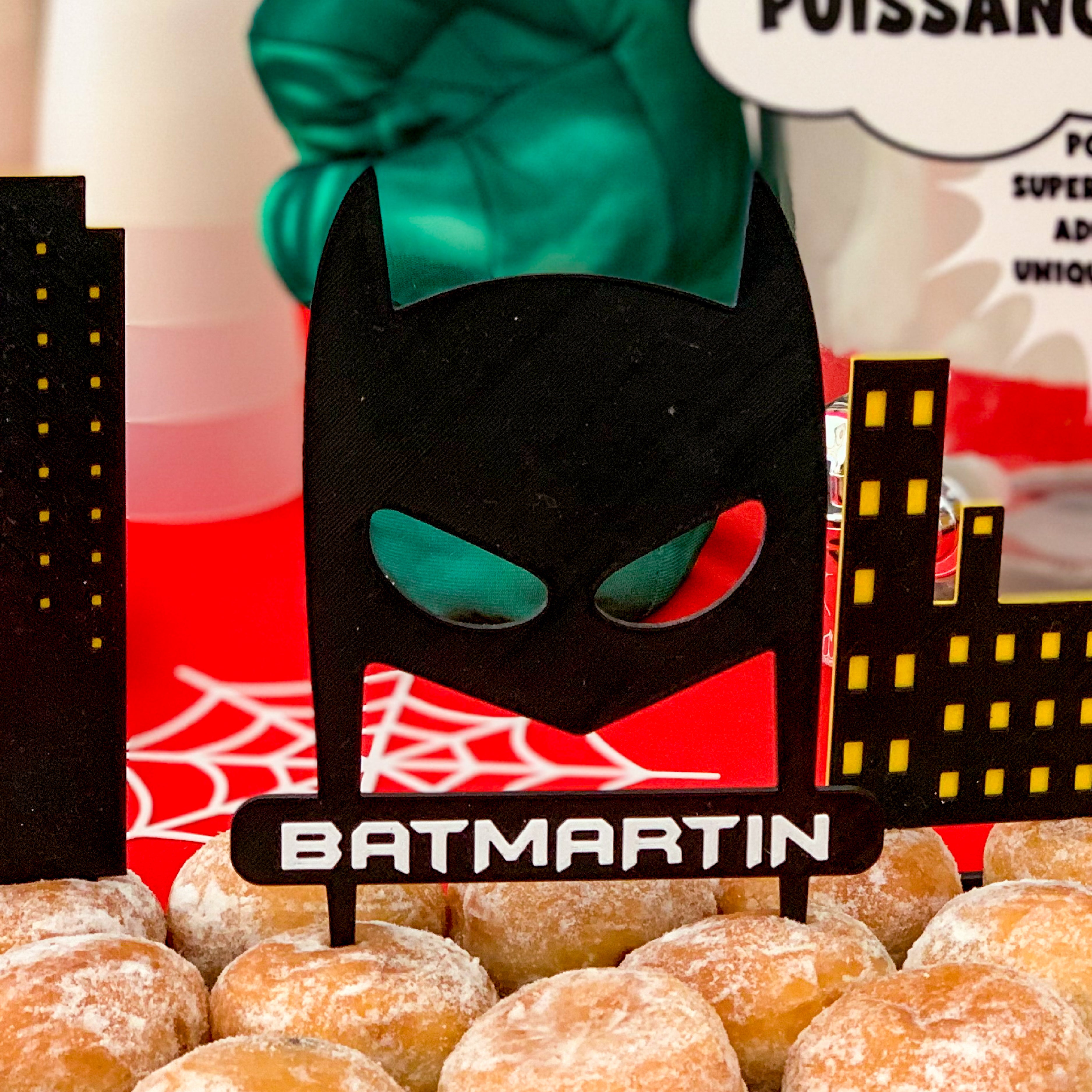 Table anniversaire super-héros avec un Cake topper personnalisé avec décor d’immeubles pour gâteau d’anniversaire enfant sur thème héros urbain.