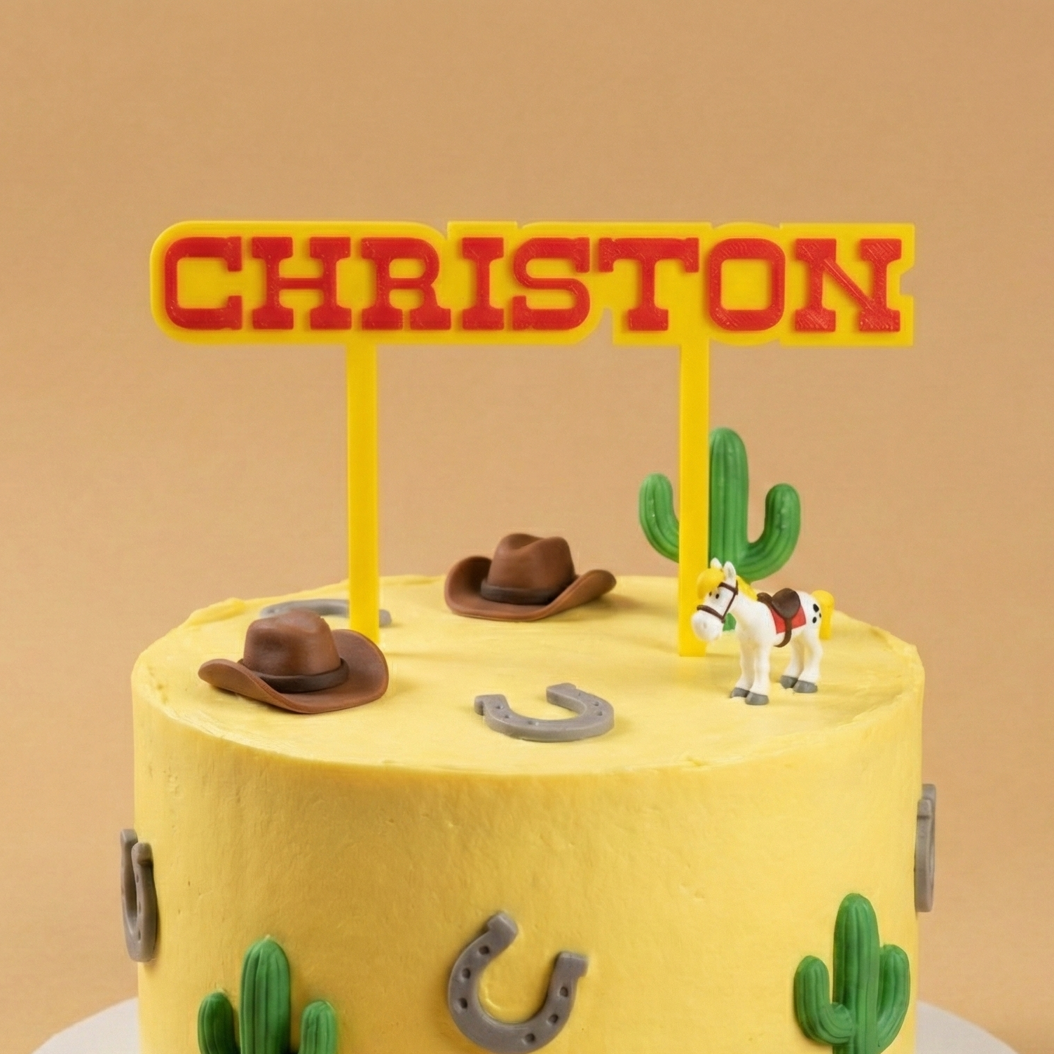 Cake topper personnalisé prénom Christon style western Lucky Luke sur gâteau d’anniversaire thème cow-boy avec cactus, chapeaux et cheval.