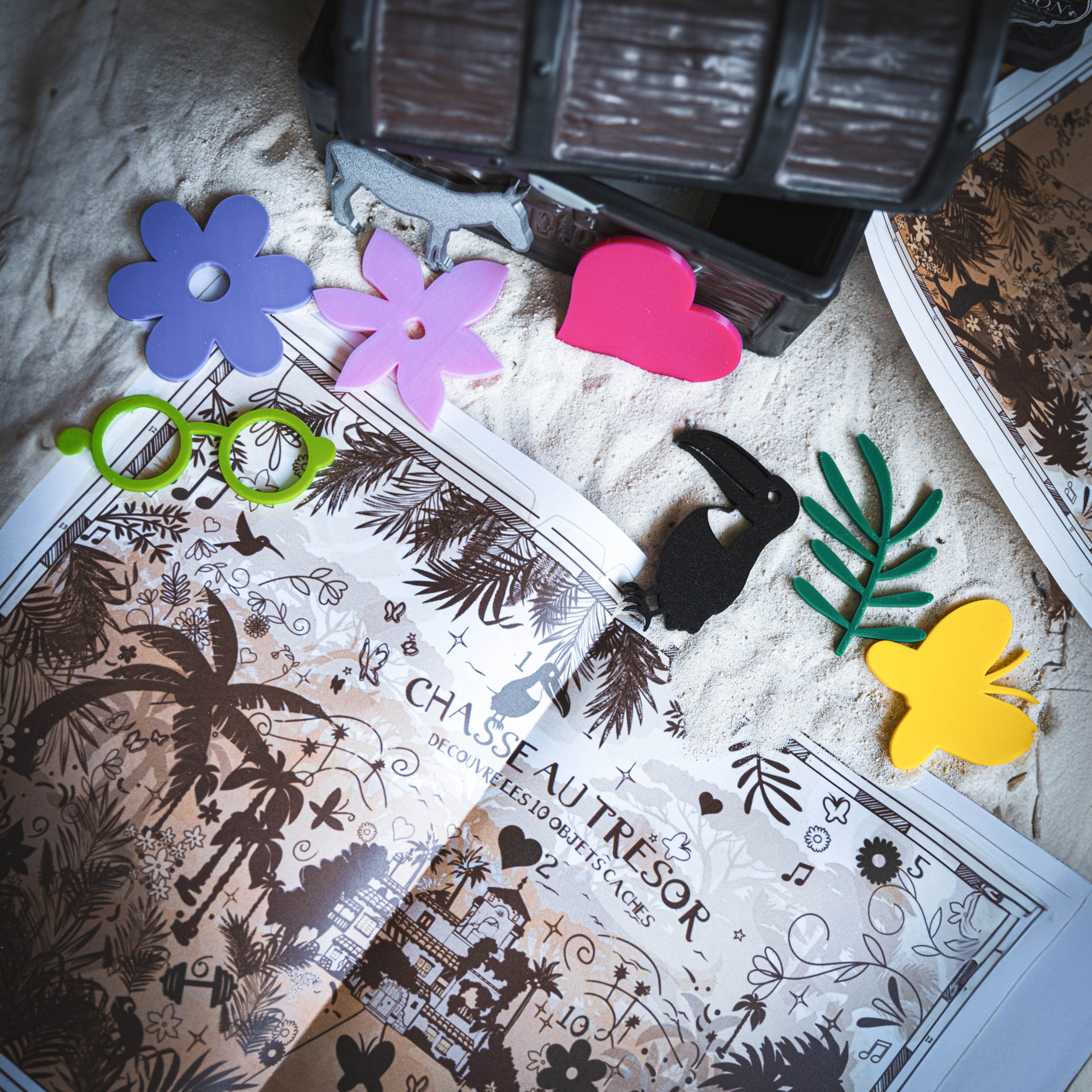 Chasse au trésor inspirée de l’univers Encanto. Carte illustrée à imprimer, accompagnée de 10 objets magiques en impression 3D à retrouver : fleurs tropicales, lunettes vertes, cœur rose, papillon, feuille, oiseau, bougie, maison magique et animal enchanté. Idéal pour un anniversaire enfant sur le thème de la Fantastique Famille Madrigal.