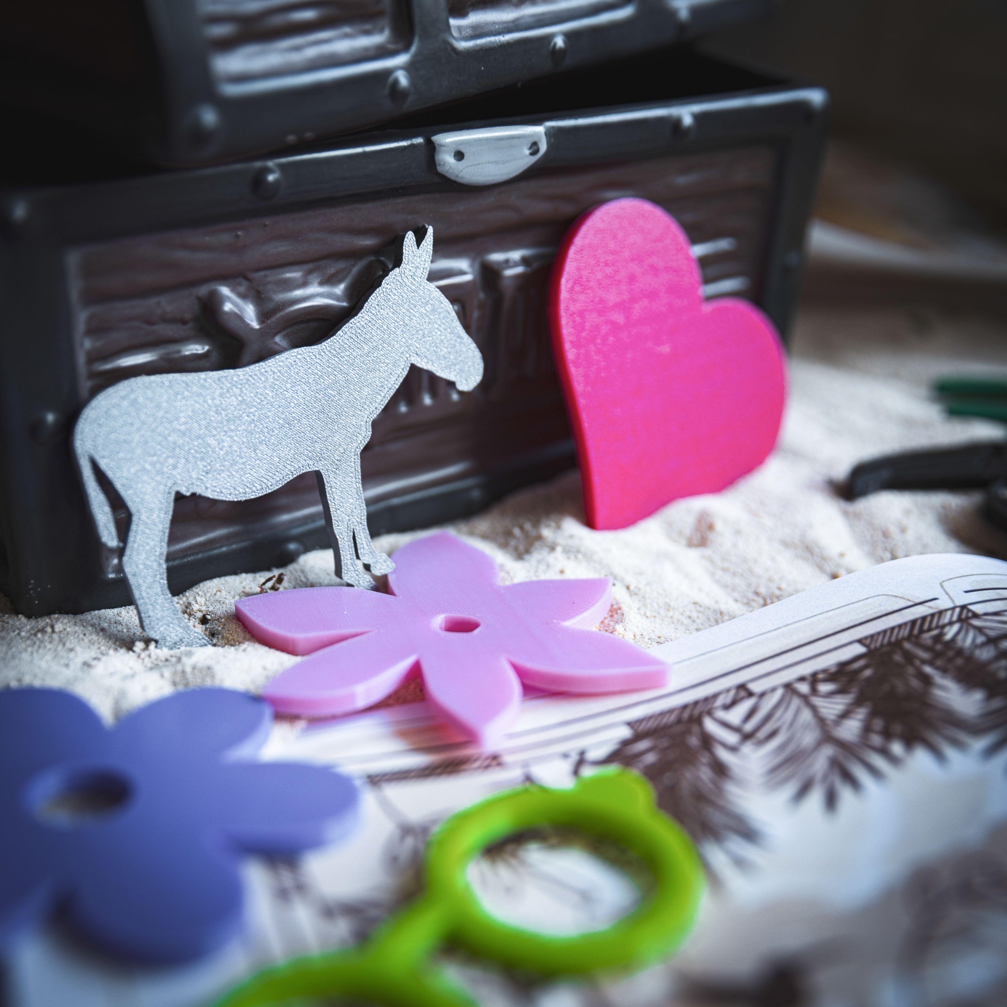 Zoom sur les objets 3D à retrouver dans la chasse au trésor "La Magie de la Vallée Cachée" : un âne argenté, un cœur rose et une fleur tropicale. Ces éléments sont à chercher sur une carte illustrée inspirée de l’univers d’Encanto. Activité magique et ludique pour enfants, idéale pour les anniversaires.