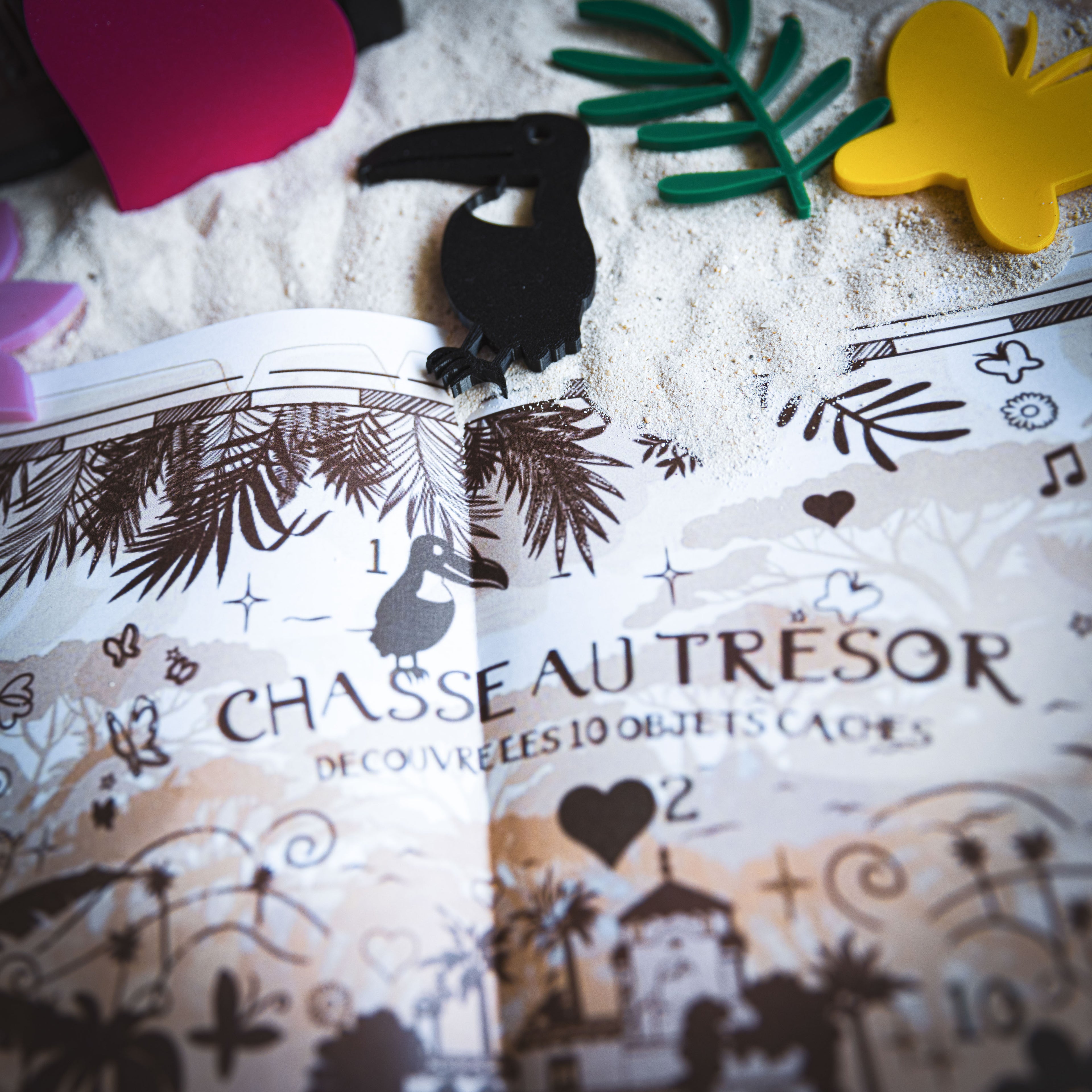Gros plan sur une chasse au trésor inspirée d’Encanto, avec carte illustrée à imprimer et objets en 3D. Le toucan noir correspond à l’objet n°1 à retrouver sur la carte. Jeu immersif magique, idéal pour animer un anniversaire sur le thème de la Vallée Cachée et de la Famille Madrigal.
