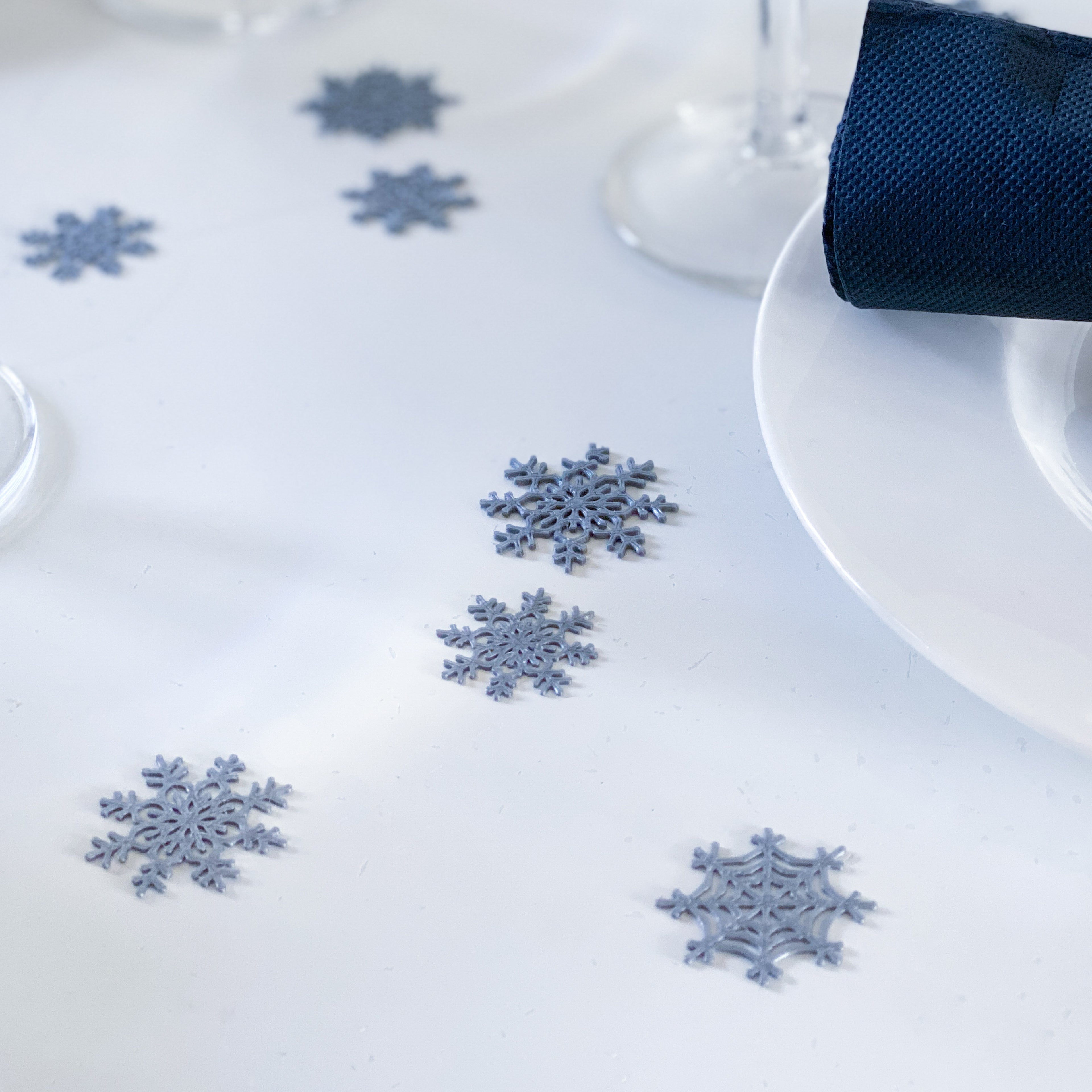Confettis flocons de neige dispersés sur une table blanche pour une décoration d’hiver élégante.