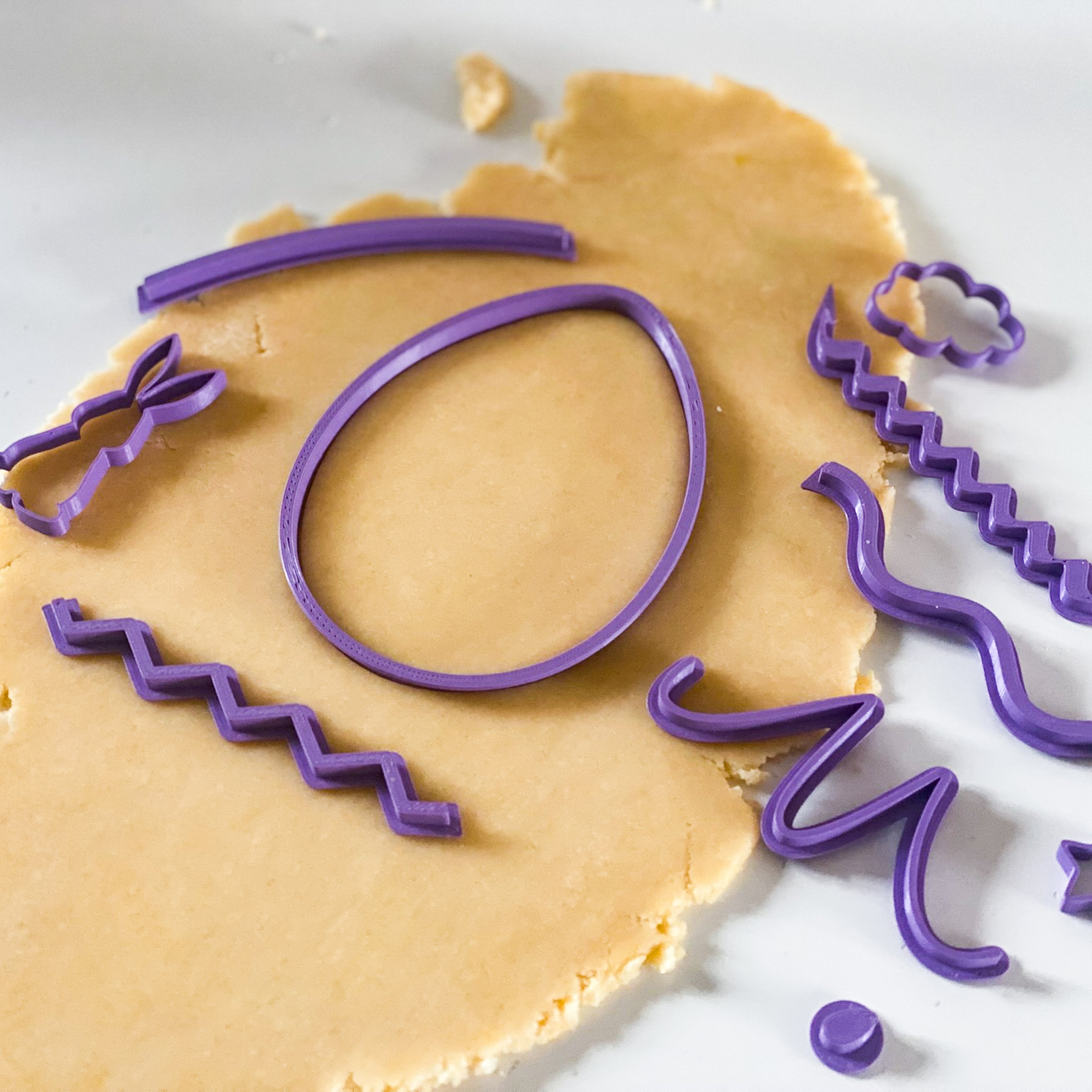 Atelier créatif avec emporte-pièce 3D œuf de Pâques et tampons motifs lapin et fleurs sur pâte sablée.