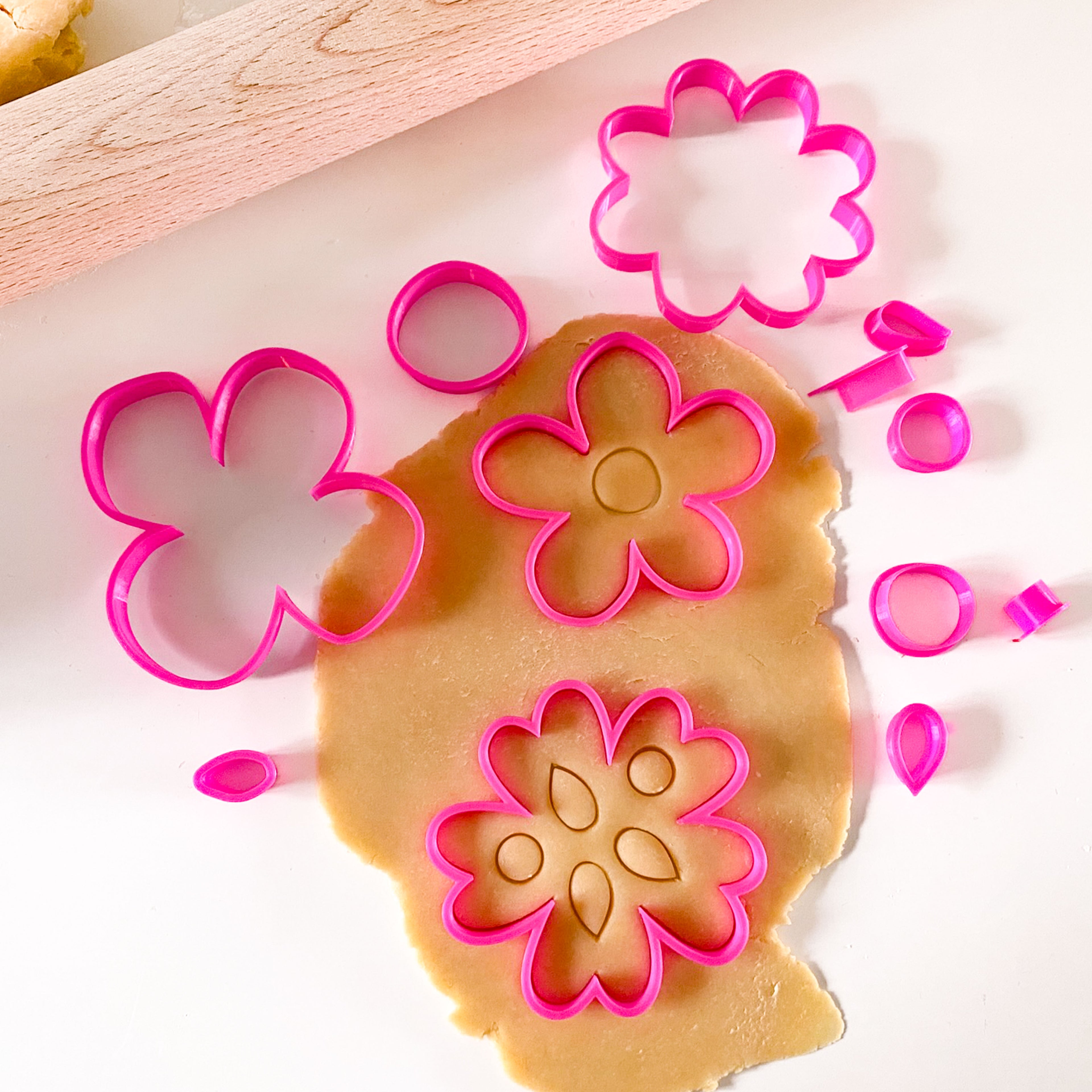 Emporte-pièces roses en forme de fleurs pour réaliser des biscuits décorés et des suspensions en pâte autodurcissante.