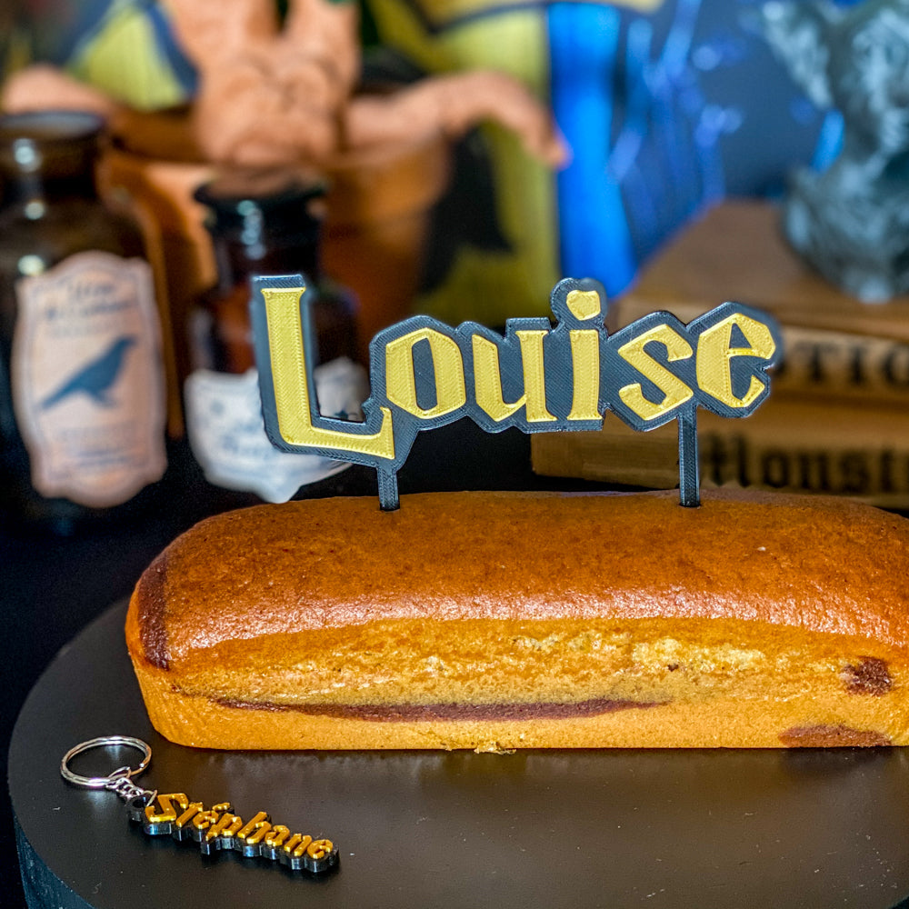 Kit personnalisé pour anniversaire thème école des sorciers Harry Potter, comprenant un grand pique à gâteau 3D noir et or au prénom 'Louise' et deux porte-clés assortis noir et or aux prénoms 'Stéphane' et 'Louise'. Le kit est présenté sur un gâteau marbré avec des bouteilles de potions et un livre ancien en arrière-plan.