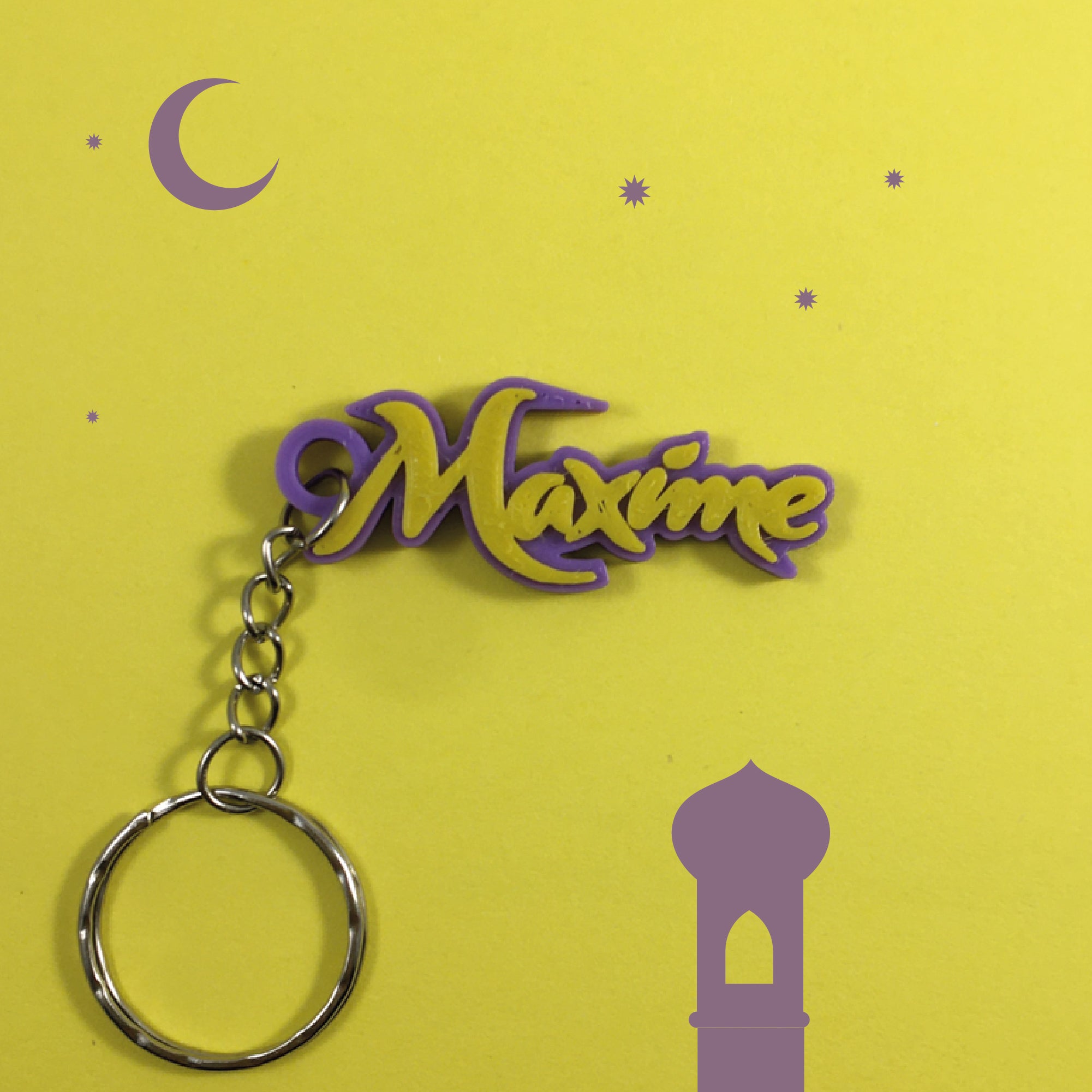 Porte-clés personnalisable au prénom Maxime, thème Mille et Une Nuits et Aladdin, avec lettres jaune-or sur base violette, sur fond jaune décoré de silhouettes violettes de croissant de lune, étoiles et minaret.