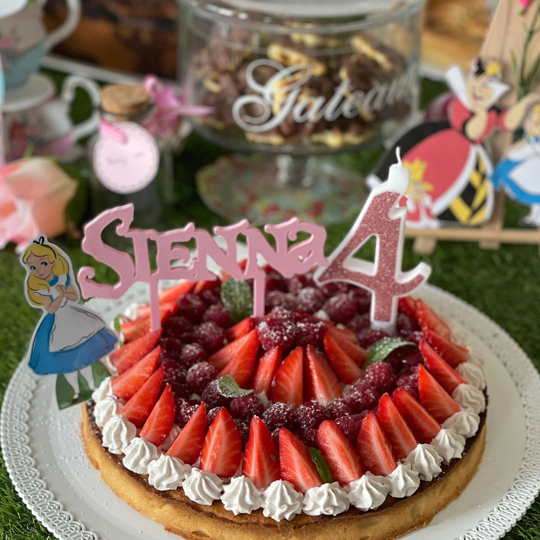 Cake topper personnalisé prénom Sienna style Alice au pays des merveilles sur gâteau d’anniversaire avec fraises, bougie chiffre 4 et décor féerique.