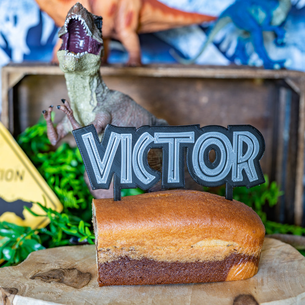 Cake topper prénom Victor style Jurassic posé sur gâteau d’anniversaire thème dinosaures, décoration personnalisée en impression 3D