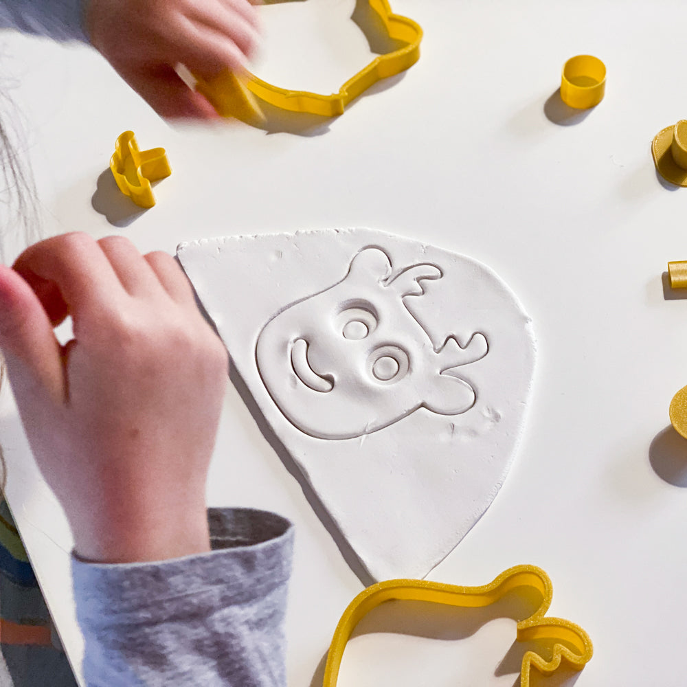 Enfant utilisant un emporte-piece jaune du kit CililaCreation pour creer une tete de renne en pate autodurcissante blanche, activite creative de Noel.