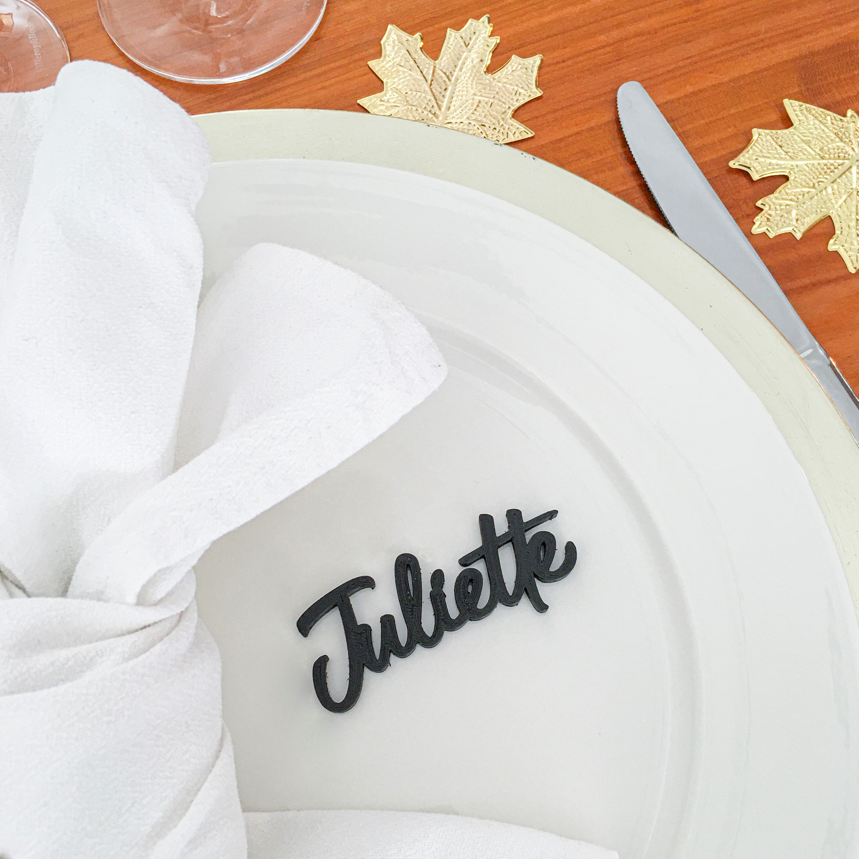 Marque-place prénom Juliette en impression 3D noir posé sur une assiette blanche, décoration raffinée pour mariage ou événement chic.