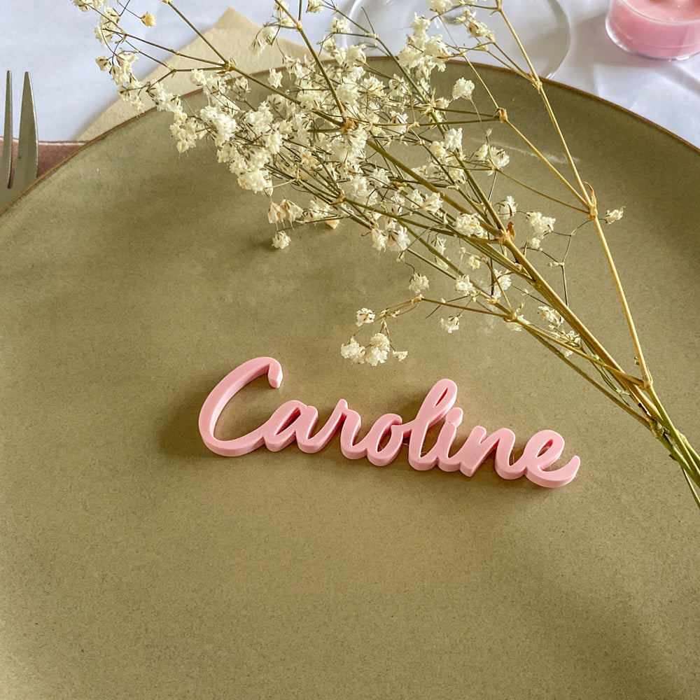 Marque-place prénom Caroline en 3D rose pastel posé sur une assiette, décoration raffinée pour table de mariage ou événement.
