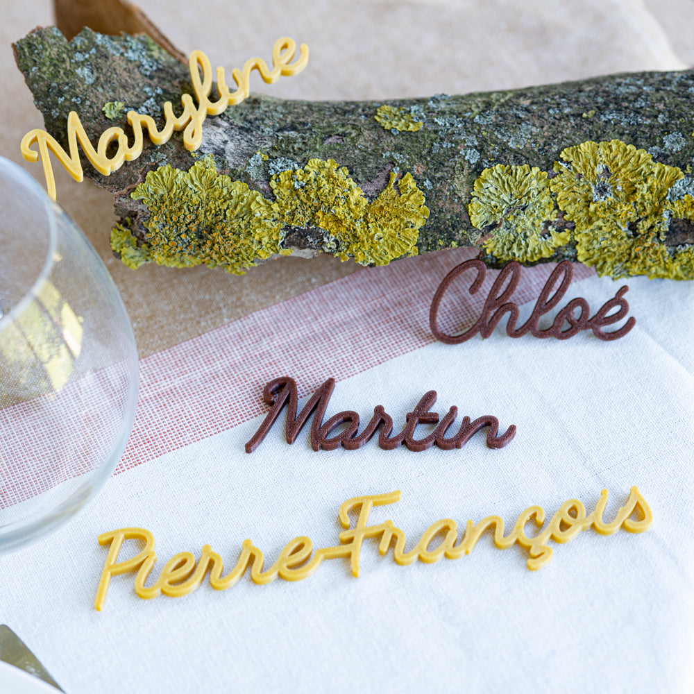 Marque-places Rétro personnalisés aux prénoms Maryline, Chloé, Martin et Pierre-François, présentés sur une table décorée avec une branche de mousse pour une ambiance chaleureuse et naturelle.