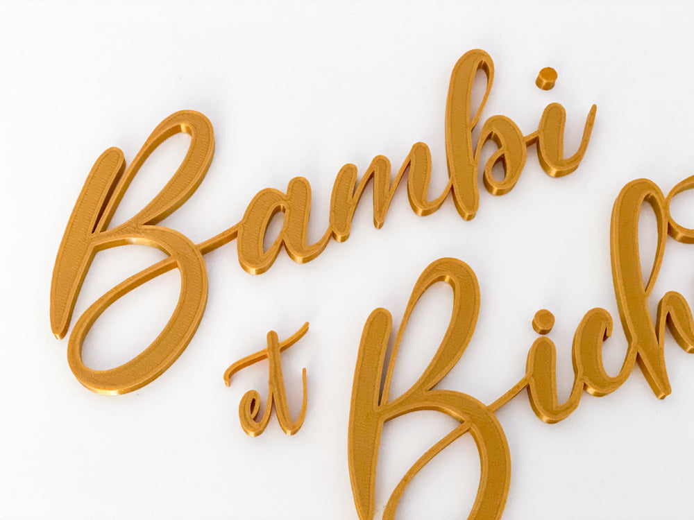 Détail des prénoms « Bambi et Bichette » en impression 3D PLA doré, écriture cursive, sur fond blanc.