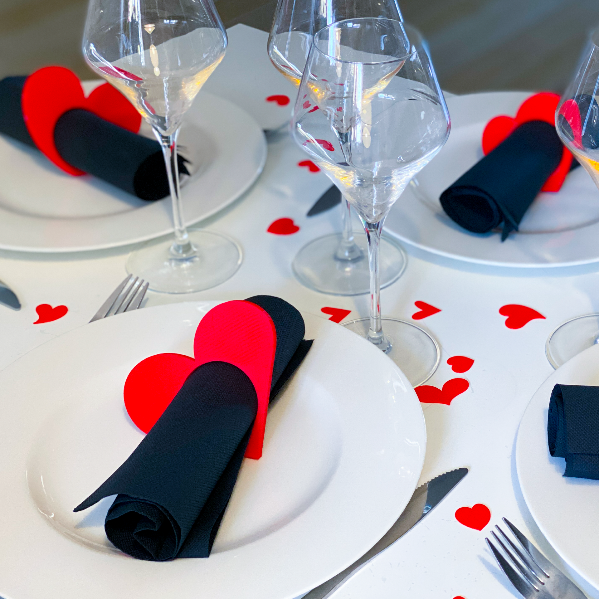 Rond de serviette en forme de cœurs rouges et noirs présenté sur une table dressée pour un repas romantique.