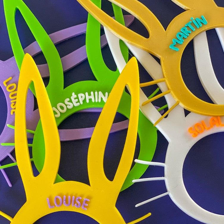 Ronds de serviette lapin de Pâques personnalisés avec plusieurs prénoms, présentés en assortiment de couleurs vives : jaune, vert, blanc, violet et doré.