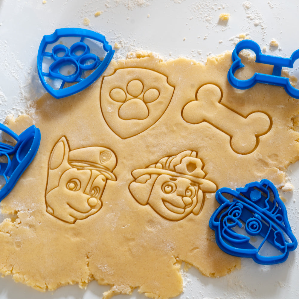 Emporte-pièces Pat Patrouille réalisant des empreintes de Marshall, Chase, un os et un écusson patte dans une pâte à biscuits